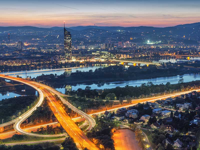 Luftaufnahme des Wiener Stadtbildes mit Donau und Autobahnkreuz am Abend