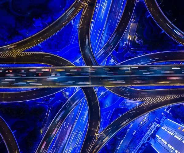 Eine Luftaufnahme von Shanghais neonbeleuchteter Autobahnkreuzung, über die sich der Verkehr bewegt.