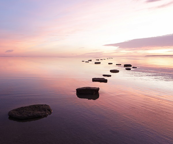 Trittsteine über ruhigem Wasser bei Sonnenuntergang