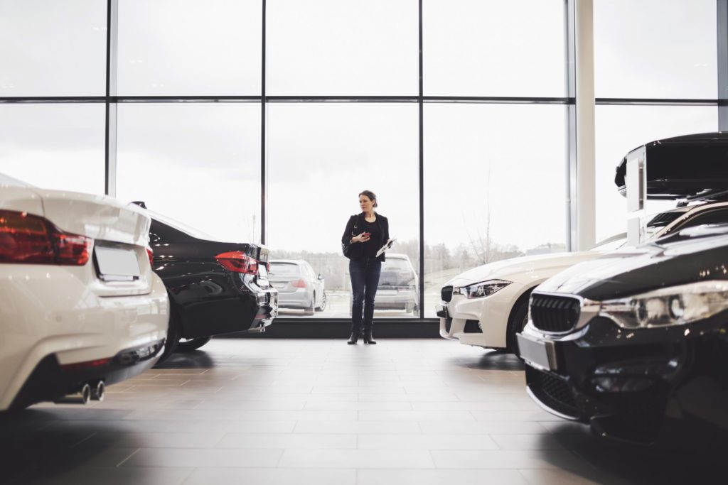 eine Frau steht in einem Autohaus und sieht sich Fahrzeuge an